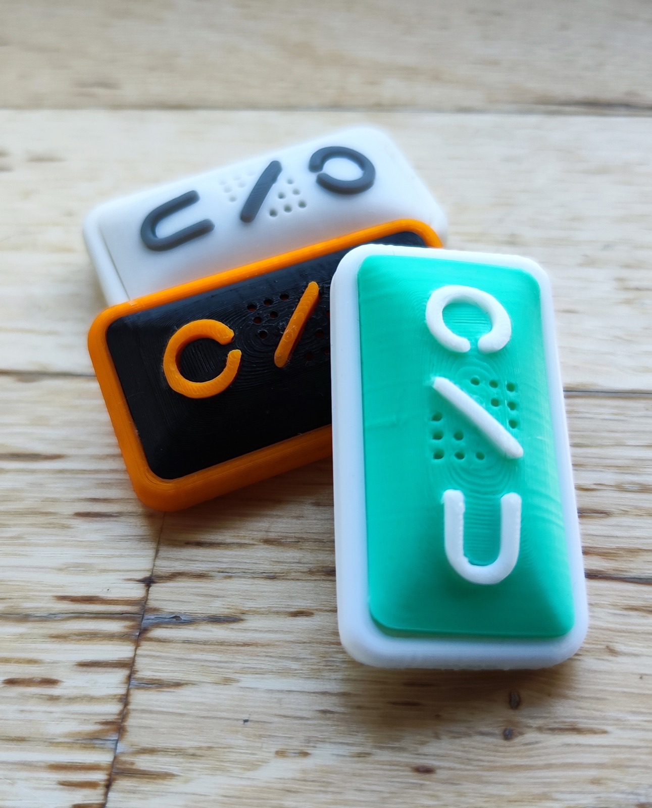 Three colourway and finish studies of the ONU enclosure on a wooden surface